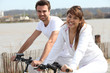 young couple doing bike near the sea