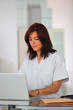 Nurse in scrubs using a laptop
