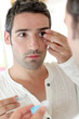 Man in front of mirrror putting ocular lens
