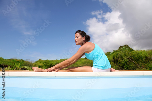 Foto: Woman doing stretching exercises by a pool Woman doing stretching exercises by a pool
