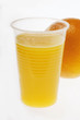 Orange juice in plastic tumbler in front of orange