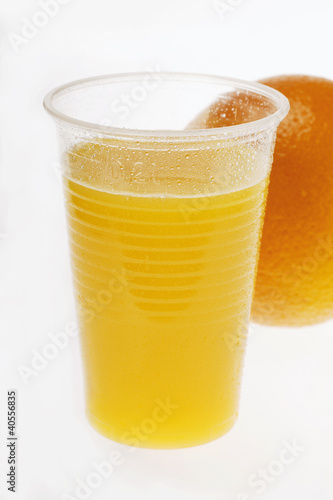 Photo: Orange juice in plastic tumbler in front of orange Orange juice in plastic tumbler in front of orange