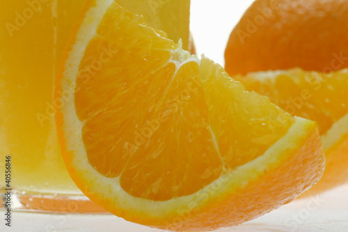 Photo: Wedge of orange in front of glass of orange juice (close-up) Wedge of orange in front of glass of orange juice (close-up)