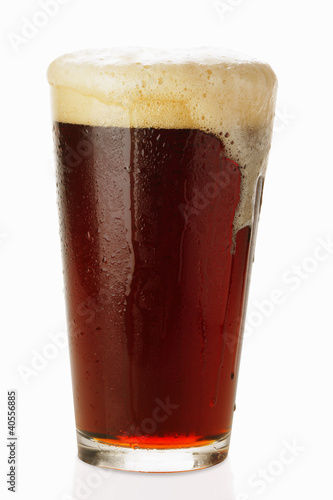 Photo: Dark beer in glass, frothing over Dark beer in glass, frothing over