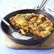Potato tortilla with chorizo in frying pan