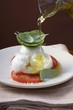 Drizzling insalata caprese with olive oil