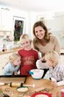 Photo: Mother and three children in kitchen baking biscuits Mother and three children in kitchen baking biscuits