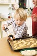 Photo: Boy piping biscuit dough onto baking tray with biscuit syringe Boy piping biscuit dough onto baking tray with biscuit syringe