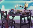 Cheese board, olives, white bread & red wine on table by pool