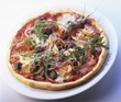 Pizza topped with prosciutto, olives, capers and rocket