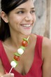 Young woman with tomato and mozzarella skewer