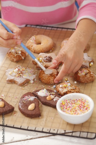 Photo: A girl decorating biscuits with icing sugar A girl decorating biscuits with icing sugar