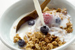 Pouring milk over crunchy muesli with berries