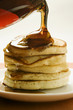 Pouring maple syrup over pancakes