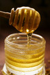 Honey running from honey dipper into honey jar