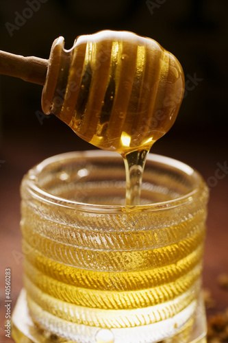 Photo: Honey running from honey dipper into honey jar Honey running from honey dipper into honey jar