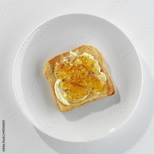 Photo: A slice of toast with butter and marmalade on a plate A slice of toast with butter and marmalade on a plate