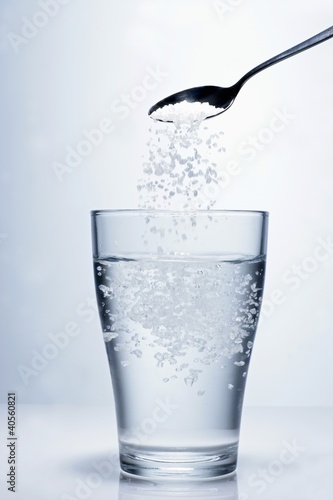 Photo: Sprinkling salt into a glass of water Sprinkling salt into a glass of water