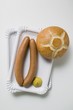 Sausages with mustard and roll on two paper plates