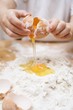 Child breaking an egg onto a heap of flour