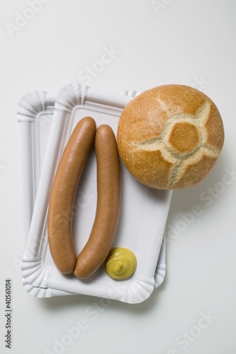 Photo: Sausages with mustard and roll on two paper plates Sausages with mustard and roll on two paper plates