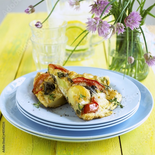 Photo: Two pieces of vegetable frittata on a pile of plates Two pieces of vegetable frittata on a pile of plates