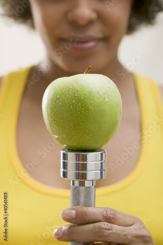 Photo: Young woman balancing a fresh apple on a hand weight Young woman balancing a fresh apple on a hand weight