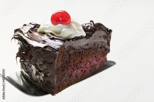 Photo: Slice of chocolate cake with cream & cherry on cake server Slice of chocolate cake with cream & cherry on cake server