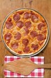 Whole pepperoni pizza, server on napkin beside it