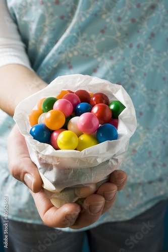 Photo: Hands holding coloured bubble gum balls in paper bag Hands holding coloured bubble gum balls in paper bag