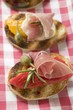 Several crostini with raw ham, peppers and giant capers