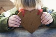 Small boy holding gingerbread heart in front of his face