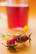 Rose hip tea in glass cup, sprig of fresh rose hips