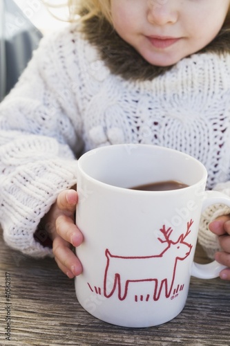 Photo: Small girl drinking large mug of cocoa Small girl drinking large mug of cocoa