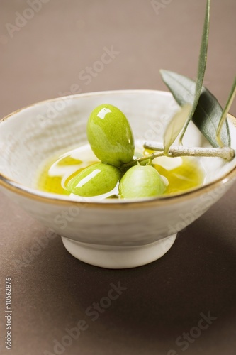 Foto: Green olives on twig in bowl of olive oil Green olives on twig in bowl of olive oil