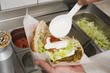 Adding yoghurt to pita bread filled with falafel