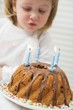 Small girl blowing out candles on birthday cake