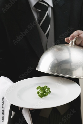 Foto: Butler serving fresh parsley on plate with dome cover Butler serving fresh parsley on plate with dome cover