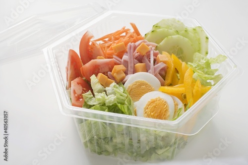 Photo: Iceberg lettuce, ham, cheese, egg & vegetables in plastic bowl Iceberg lettuce, ham, cheese, egg & vegetables in plastic bowl