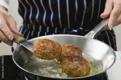 Photo: Woman frying burgers in a frying pan Woman frying burgers in a frying pan