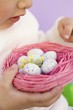 Child holding Easter eggs in pink nest