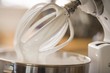 Whipped cream on balloon whisk of food mixer