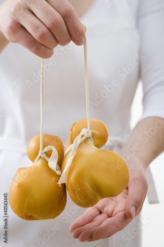 Foto: Woman holding two Provolone cheeses Woman holding two Provolone cheeses