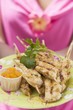 Foto: Woman holding plate of satay and chutney Woman holding plate of satay and chutney