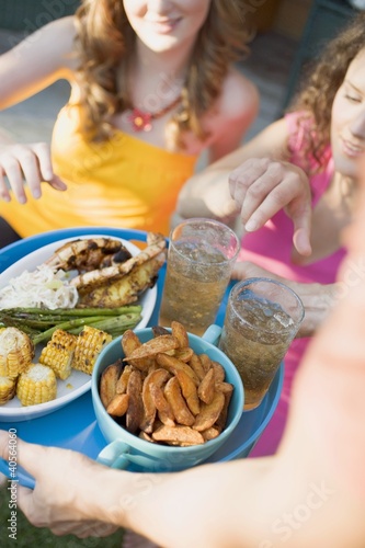 Photo: Man serving two women with tray of grilled food & iced tea Man serving two women with tray of grilled food & iced tea