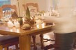 Woman bringing plates to table laid for Christmas