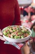 Woman holding dish of Brussels sprouts with bacon (Christmas)