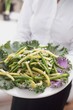 Woman holding plate of beans with flaked almonds