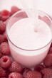Raspberry shake in glass, surrounded by fresh raspberries