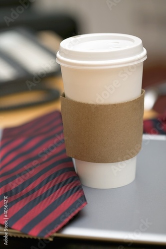 Photo: Coffee cup and tie on desk in office Coffee cup and tie on desk in office